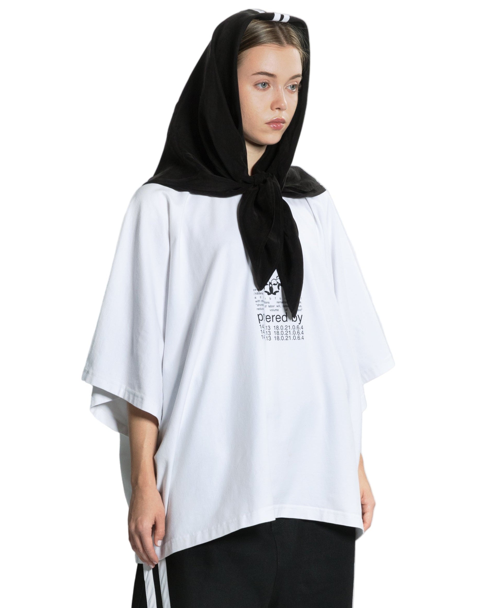 Person wearing a white oversized shirt and black pants with white stripes on a white background